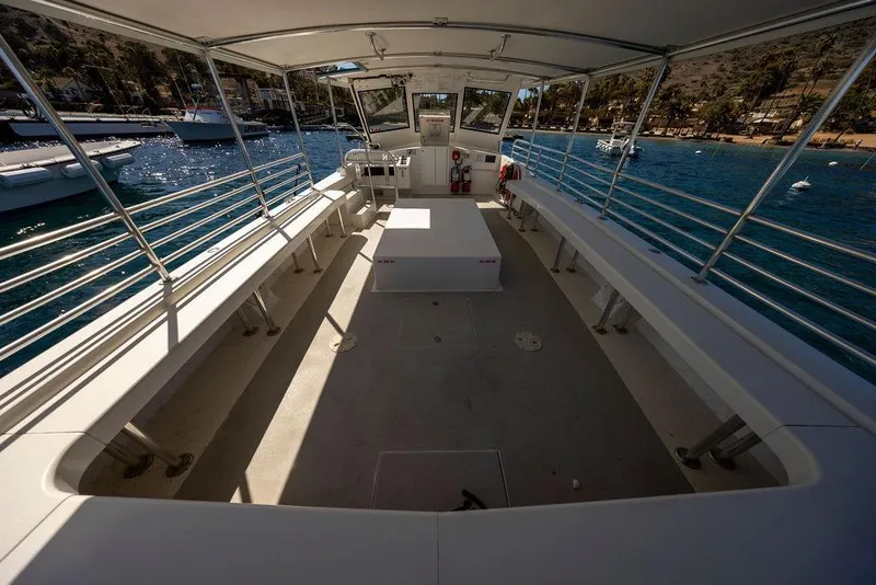 Slide: The Image of 2018 Seahawk Island Hopper boat interior with seating, docked by a scenic coastline. - 9