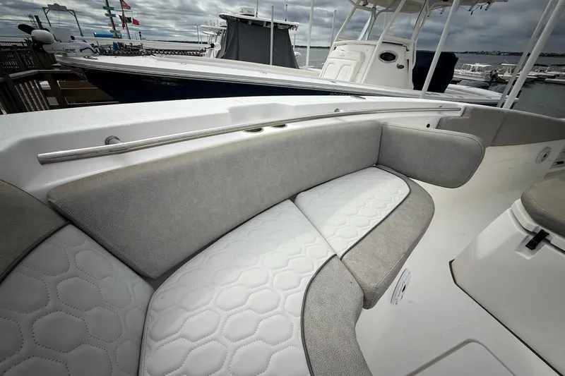 Slide: The Image of 2022 Sea Fox 288 Commander boat with cushioned seating and sleek design at a marina. - 16