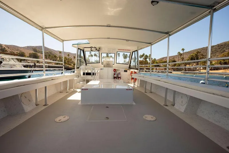 Slide: The Image of 2019 Seahawk Island Hopper boat interior with open seating, docked near scenic coastline. - 10