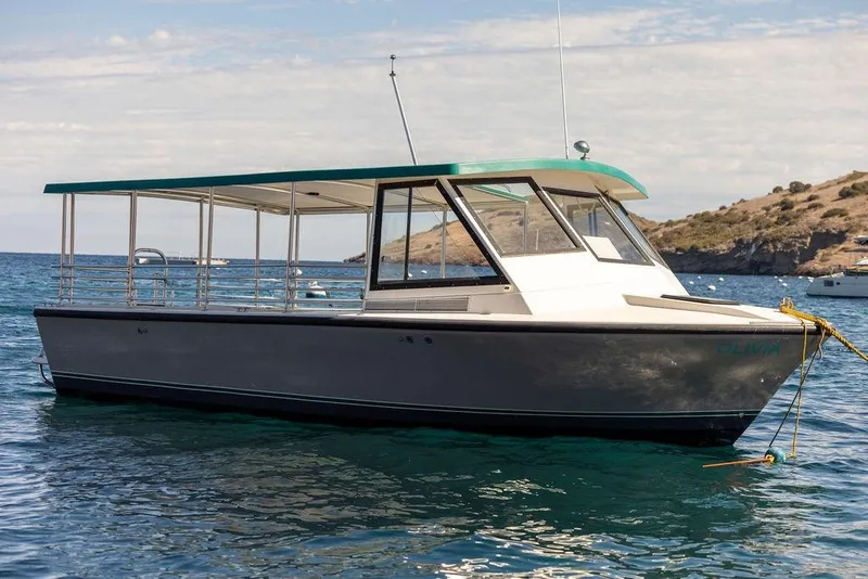 Slide: The Image of 2019 Seahawk Island Hopper boat anchored in clear blue water near a rocky coastline. - 2