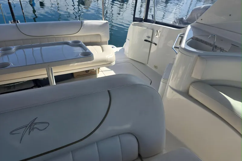 Slide: The Image of 2000 Monterey 302 Cruiser interior with seating, table, and sink, docked on calm water. - 10