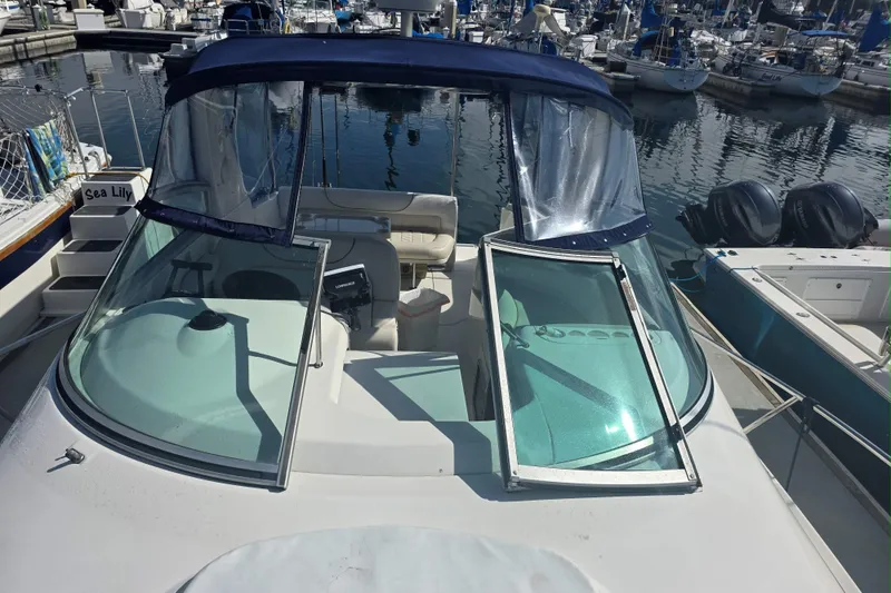 Slide: The Image of 2000 Monterey 302 Cruiser docked at marina, featuring open windshield and blue canopy. - 4