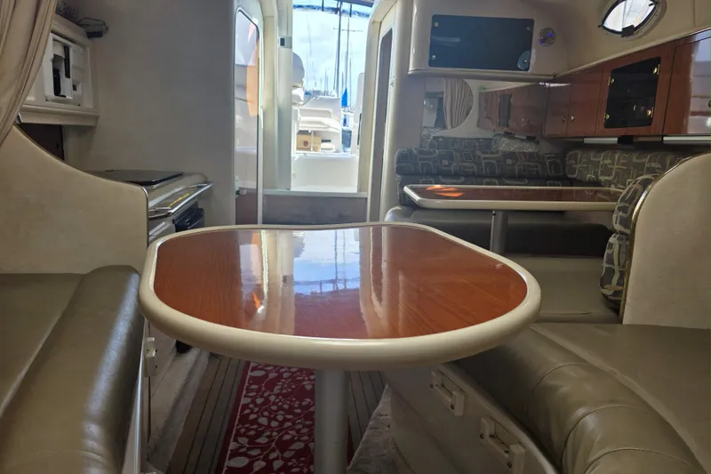 Slide: The Image of Interior of a 2000 Monterey 302 Cruiser with wood-finish tables and cushioned seating. - 8