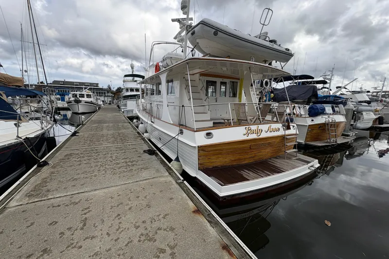 The Image of 1998 Grand Banks 52 Europa yacht on serene water with forested backdrop. - 0
