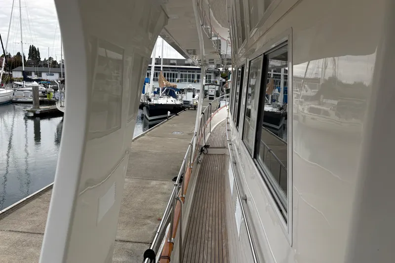 Slide: The Image of 1998 Grand Banks 52 Europa yacht docked, showcasing sleek wooden deck and marina surroundings. - 20