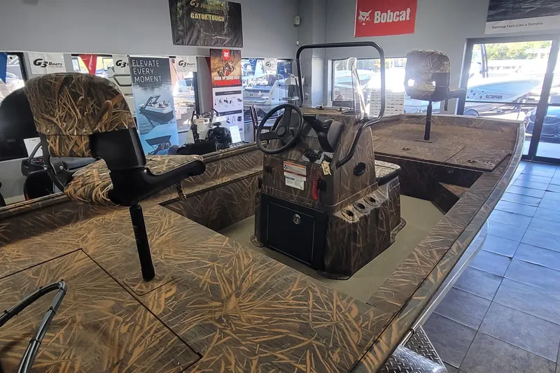 Slide: The Image of 2026 G3 17CC boat with camo design in showroom, featuring steering console and seating. - 9