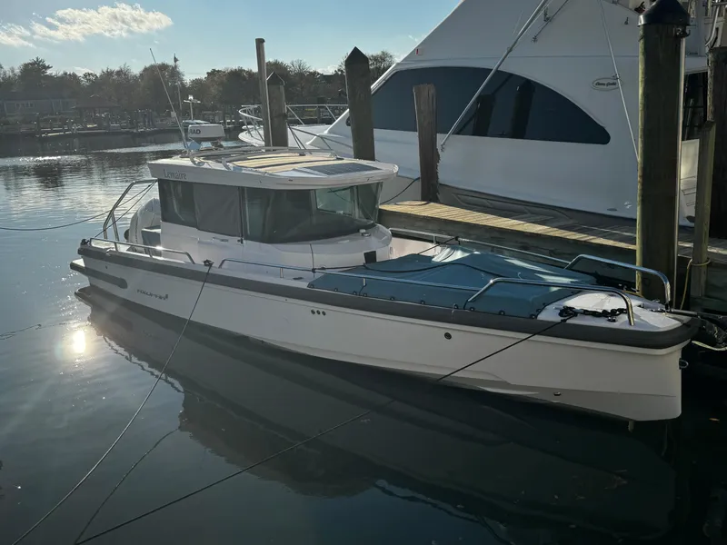 Slide: The Image of 2023 Axopar 28 CABIN boat docked in a marina, side view. - 12