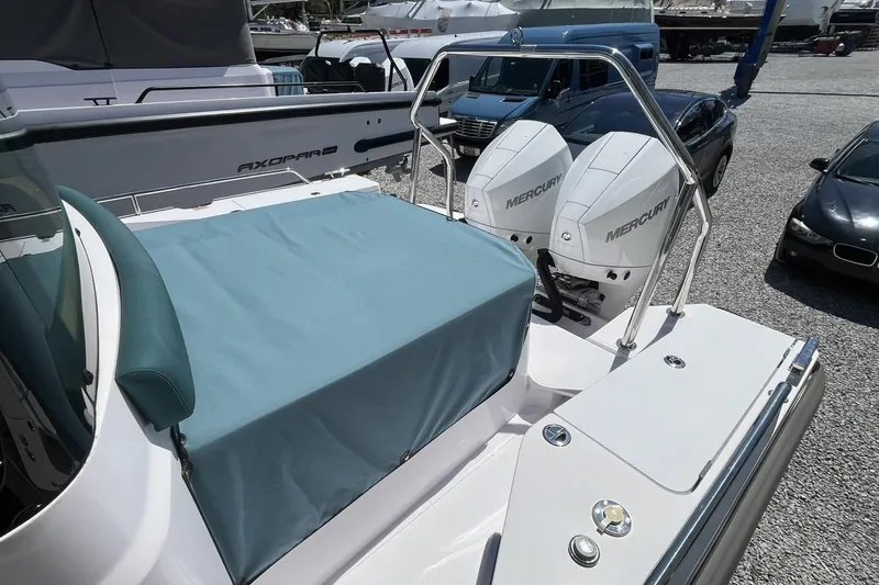 Slide: The Image of 2023 Axopar 28 Cabin boat with dual Mercury engines, parked on gravel. - 15