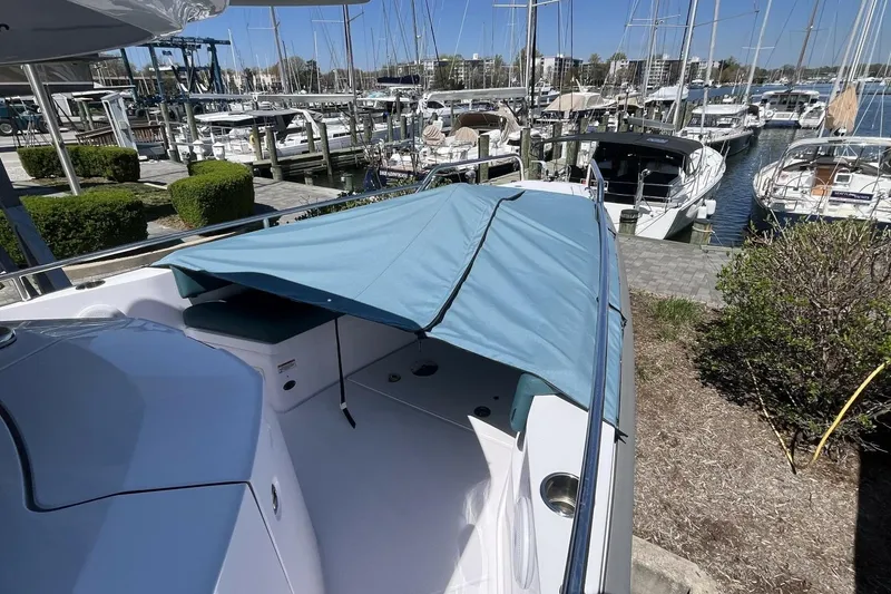 Slide: The Image of 2023 Axopar 28 Cabin boat docked at marina with blue canopy. - 18