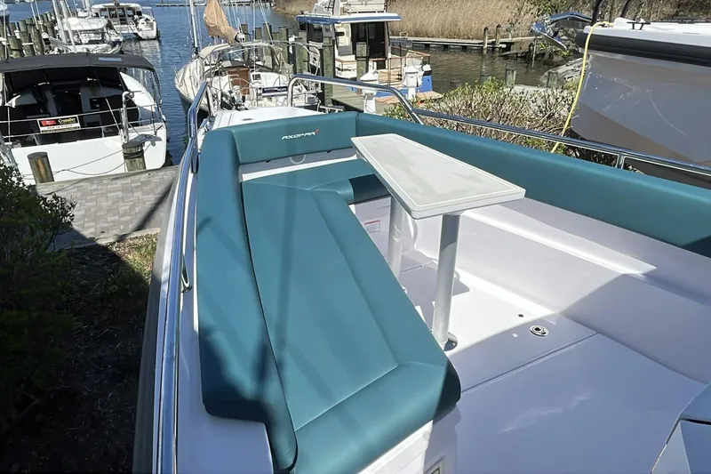 Slide: The Image of 2023 Axopar 28 Cabin boat with teal seating and table, docked at marina. - 23