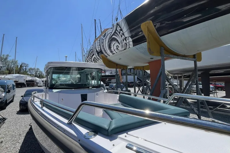Slide: The Image of 2023 Axopar 28 Cabin boat in a marina, surrounded by other vessels. - 25