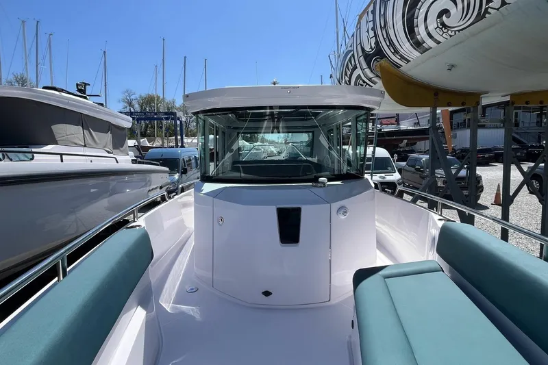 Slide: The Image of 2023 Axopar 28 Cabin boat with sleek design, docked among other vessels. - 27