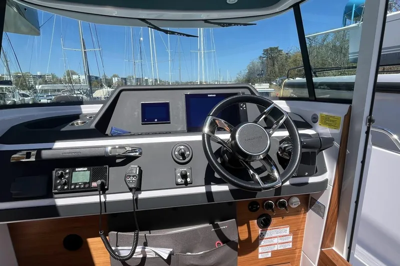 Slide: The Image of 2023 Axopar 28 Cabin helm with steering wheel and navigation controls. - 32