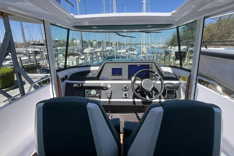 Slide: The Image of Interior view of 2023 Axopar 28 Cabin boat with modern dashboard and marina backdrop. - 34