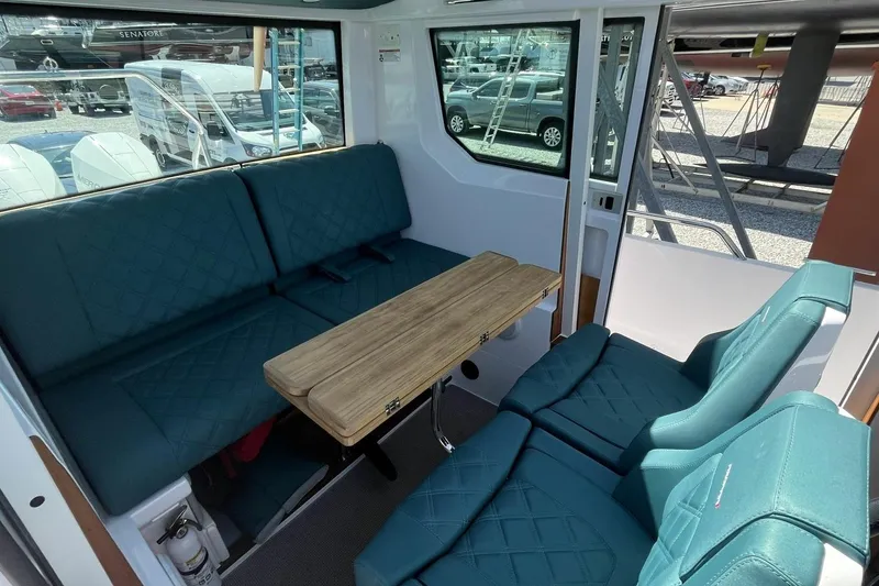 Slide: The Image of Interior of 2023 Axopar 28 Cabin with teal seating and wooden table. - 35