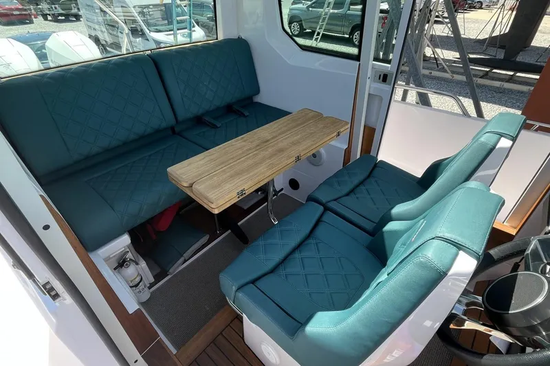 Slide: The Image of Interior of 2023 Axopar 28 Cabin with teal seating and wooden table. - 36