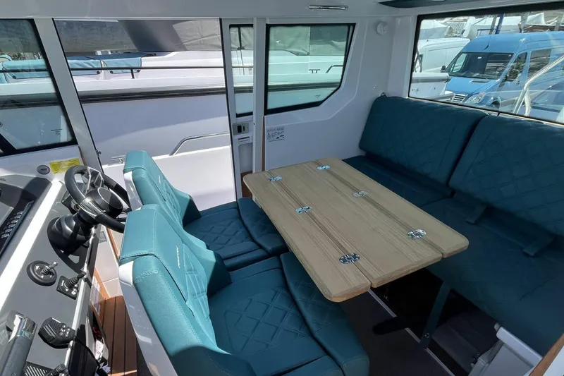 Slide: The Image of 2023 Axopar 28 Cabin interior with teal seating and wooden table. - 37