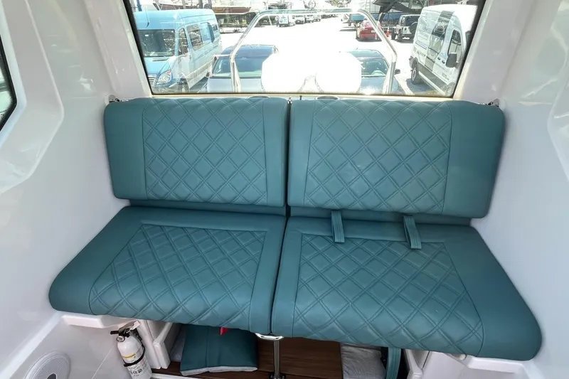 Slide: The Image of 2023 Axopar 28 Cabin interior with teal quilted seating and window view. - 39