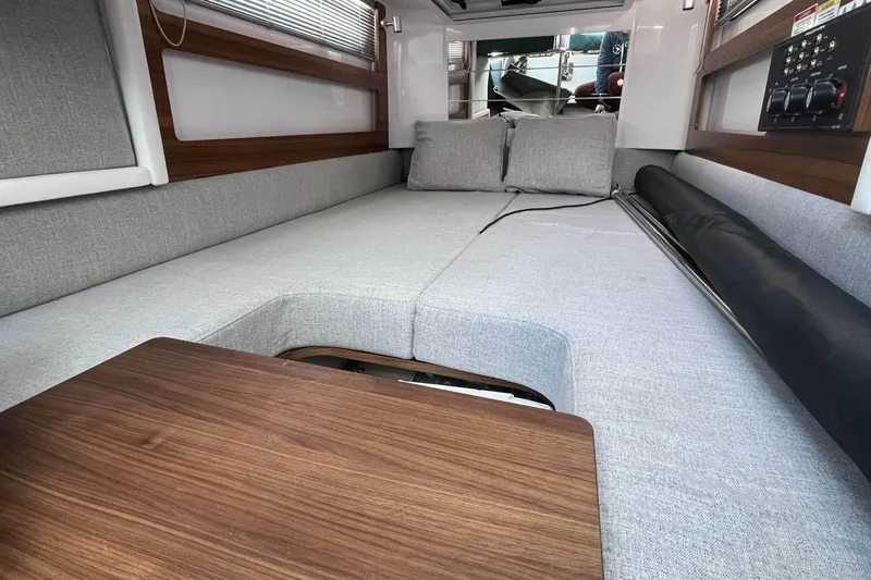 Slide: The Image of 2023 Axopar 28 Cabin interior with gray seating and wooden table. - 40