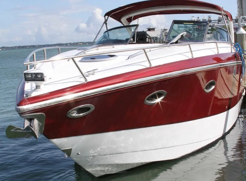 Slide: The Image of 2005 Cobalt 360 boat with red and white exterior docked on calm water. - 2