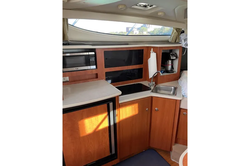 Slide: The Image of 2003 Bayliner 3055 Ciera boat kitchen with microwave, sink, and wooden cabinetry. - 10