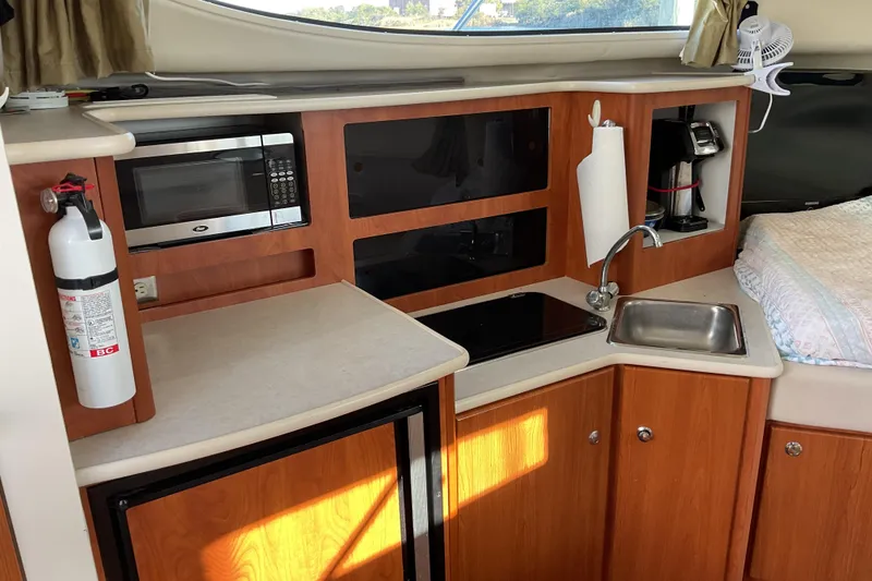 Slide: The Image of 2003 Bayliner 3055 Ciera interior kitchen with microwave, sink, and wooden cabinetry. - 9