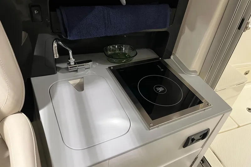 Slide: The Image of 2026 Bayliner Trophy T23 Explorer interior with sink and stove in compact kitchen area. - 8