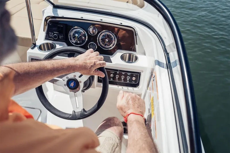 Slide: The Image of Manufacturer Provided Image: Person steering 2025 Bayliner D22 boat on water, close-up of dashboard and controls. - 4