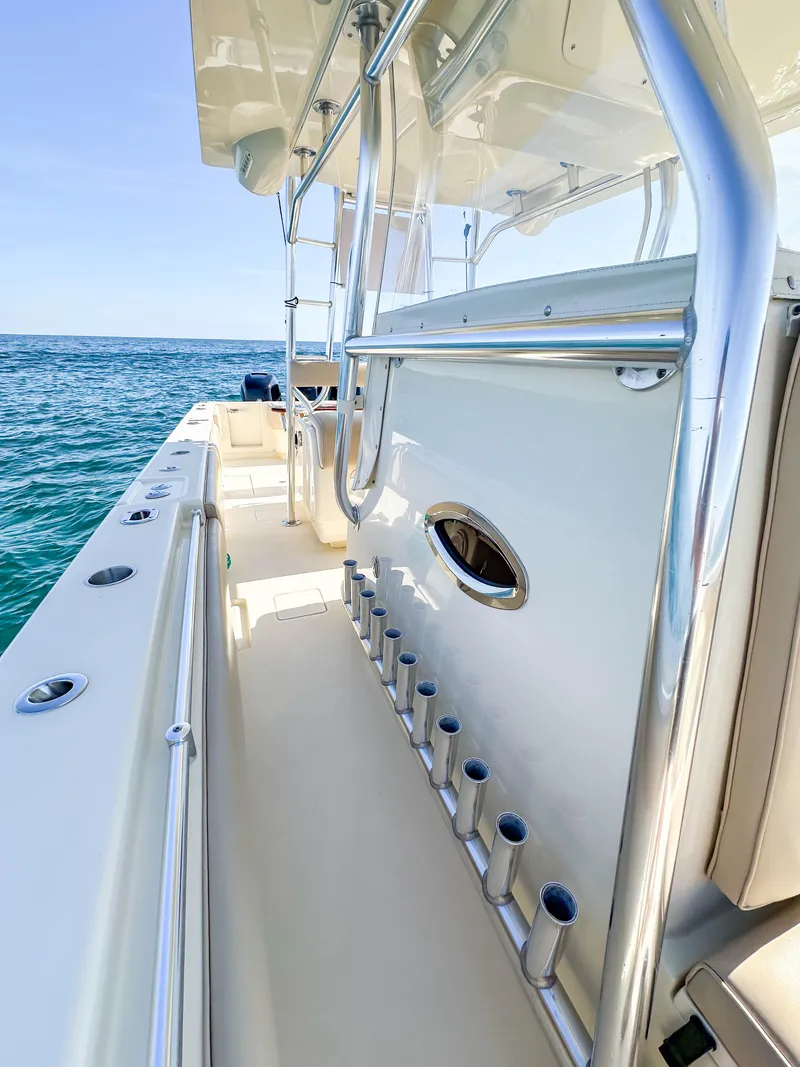 Slide: The Image of 2012 Contender 39 ST boat, side view, showing rod holders and ocean backdrop. - 20