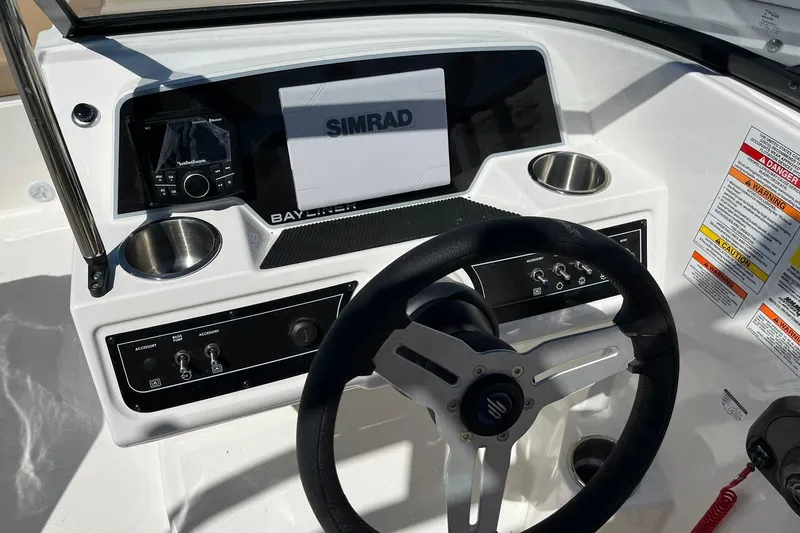 Slide: The Image of 2026 Bayliner D22 boat dashboard with steering wheel, Simrad display, and control panel. - 14