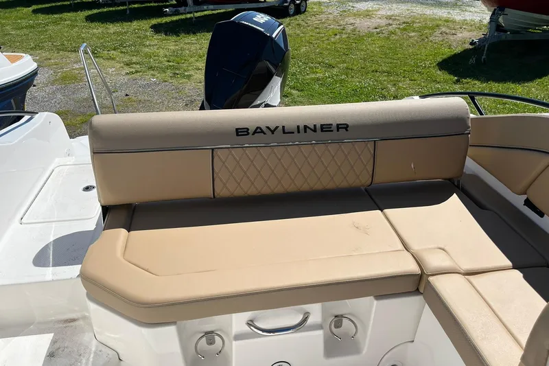 Slide: The Image of Bayliner D22 2026 boat with beige seating and outboard motor, parked on grass. - 8