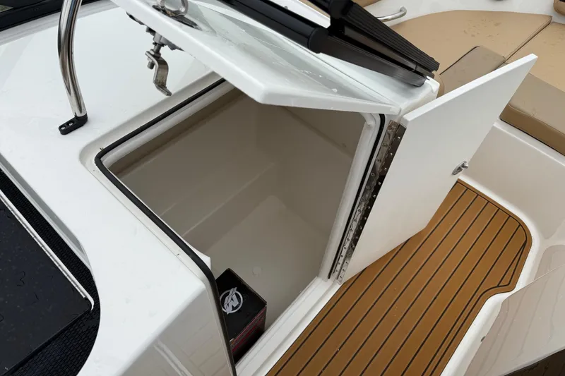 Slide: The Image of 2025 Bayliner VR6 Bowrider I/O interior with open storage compartment and tan seating. - 10