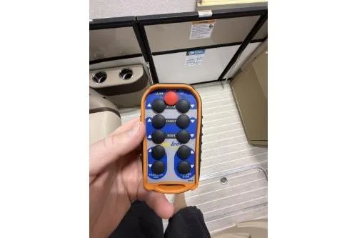 Slide: The Image of Hand holding a remote control inside a 2025 Berkshire 23ULESTS3-93 boat cabin. - 3