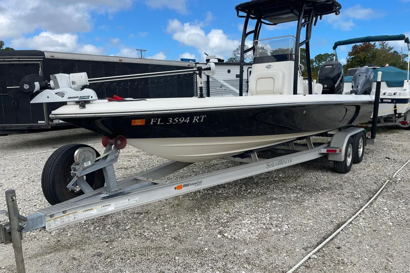 The Image of 2014 ShearWater 23TE boat on trailer, parked outdoors under a blue sky. - 0