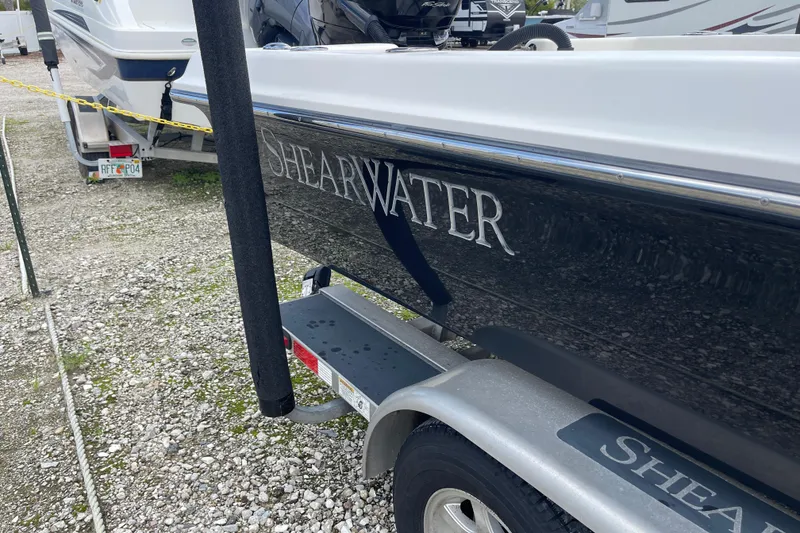 Slide: The Image of 2014 ShearWater 23TE boat on trailer in driveway, surrounded by greenery and palm trees. - 4