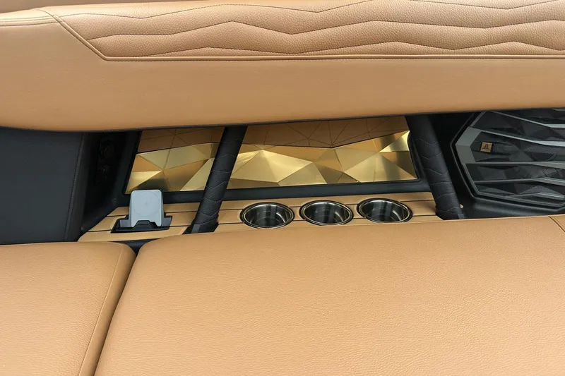 Slide: The Image of 2025 Nautique Super Air Nautique G23 interior with tan leather and cup holders. - 19