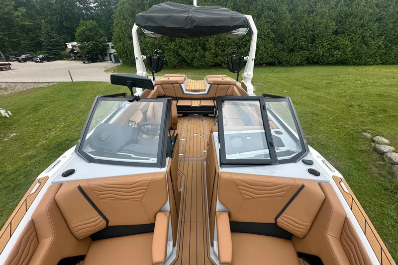 Slide: The Image of 2025 Nautique Super Air Nautique G23 boat interior with tan seating and open windshield. - 21