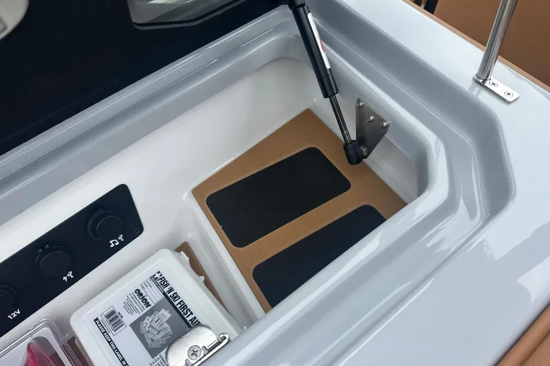 Slide: The Image of 2025 Nautique Super Air Nautique G23 storage compartment with first aid kit and controls. - 24