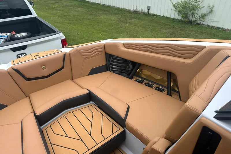 Slide: The Image of 2025 Nautique Super Air Nautique G23 interior with tan leather seating and cup holders. - 25