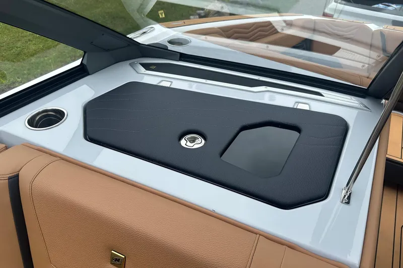 Slide: The Image of 2025 Nautique Super Air Nautique G23 interior with tan and black upholstery, cup holder, and sleek design. - 29