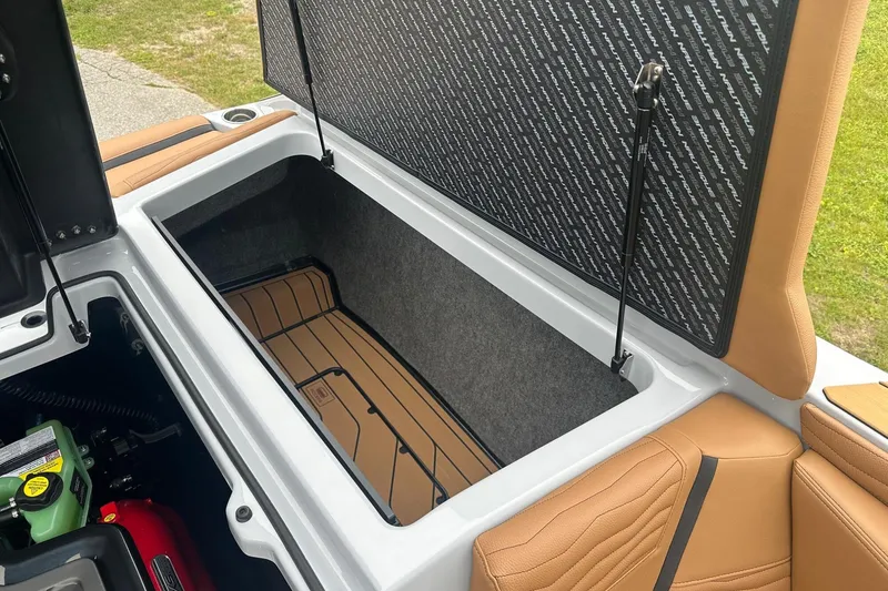 Slide: The Image of 2025 Nautique Super Air Nautique G23 storage compartment with tan upholstery and open hatch. - 31
