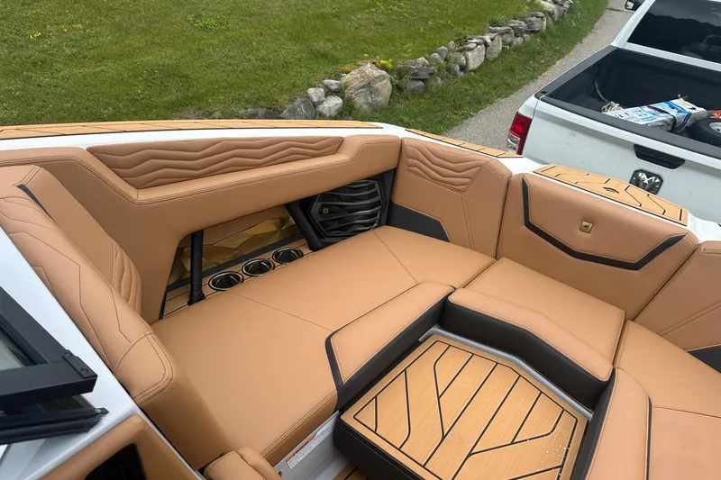 Slide: The Image of 2025 Nautique Super Air Nautique G23 interior with tan leather seating and cup holders. - 40