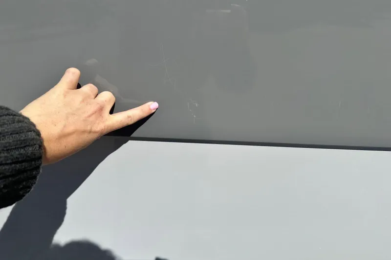 Slide: The Image of Hand pointing at scratch on 2025 Nautique Super Air Nautique G23 boat surface. - 46