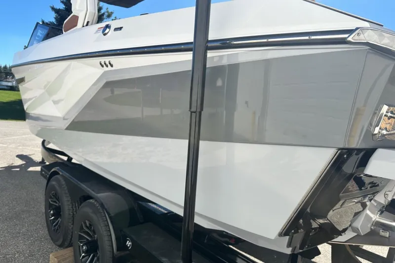 Slide: The Image of 2025 Nautique Super Air Nautique G23 boat on trailer, sleek design, white and gray exterior. - 48