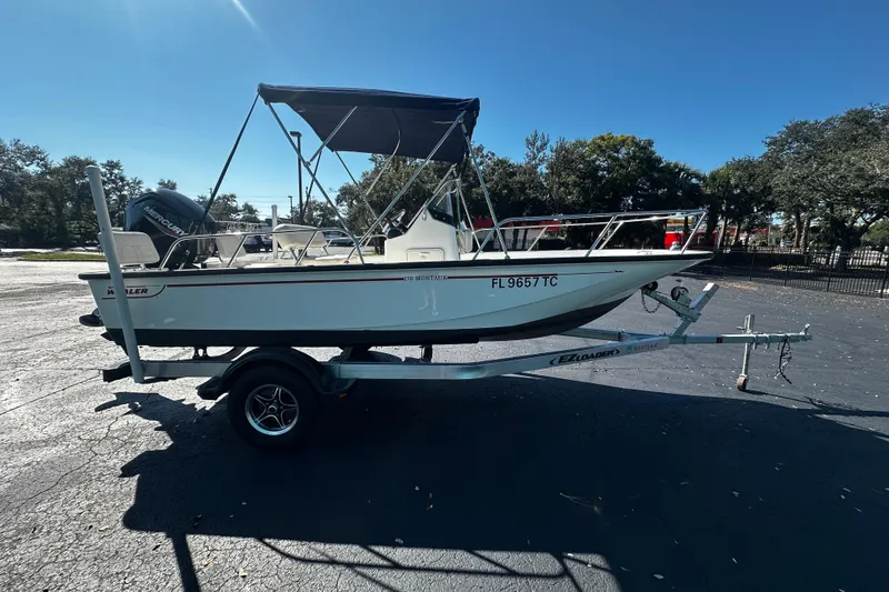 Slide: The Image of 2022 Boston Whaler 170 Montauk boat on trailer, parked outdoors under clear sky. - 1