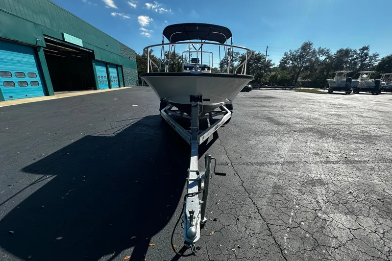 Slide: The Image of 2022 Boston Whaler 170 Montauk boat on trailer, parked outside a green building. - 3