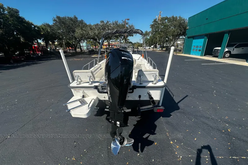 Slide: The Image of 2022 Boston Whaler 170 Montauk boat, rear view with outboard motor, parked outdoors. - 4