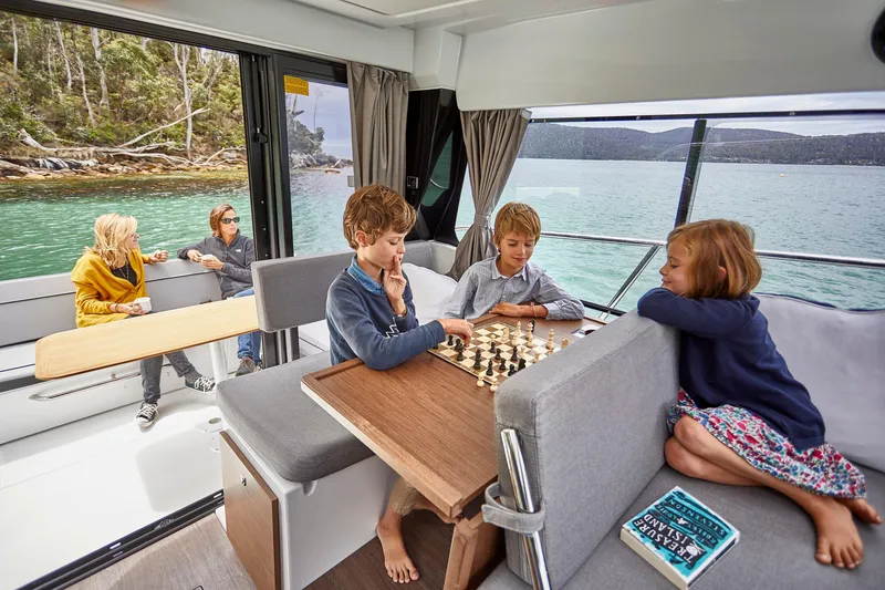 Slide: The Image of Family enjoying chess and relaxation on Jeanneau NC1095 Fly boat, 2026 model, near scenic shoreline. - 4