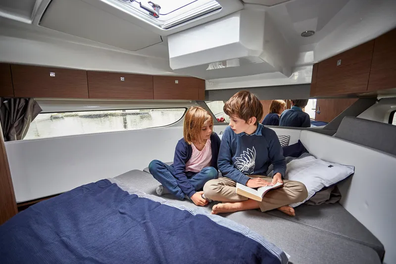 Slide: The Image of Children reading in the cozy cabin of a 2026 Jeanneau NC1095 Fly yacht. - 6