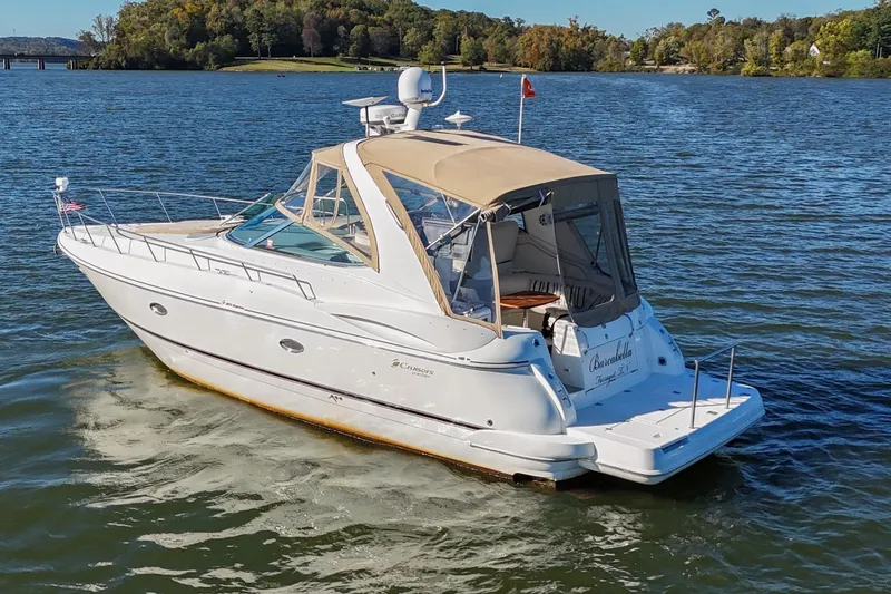 Slide: The Image of 2001 Cruisers Yachts 3672 Express on a serene lake with lush green shoreline. - 3